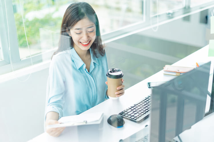 コーヒーを片手に仕事をする女性社員